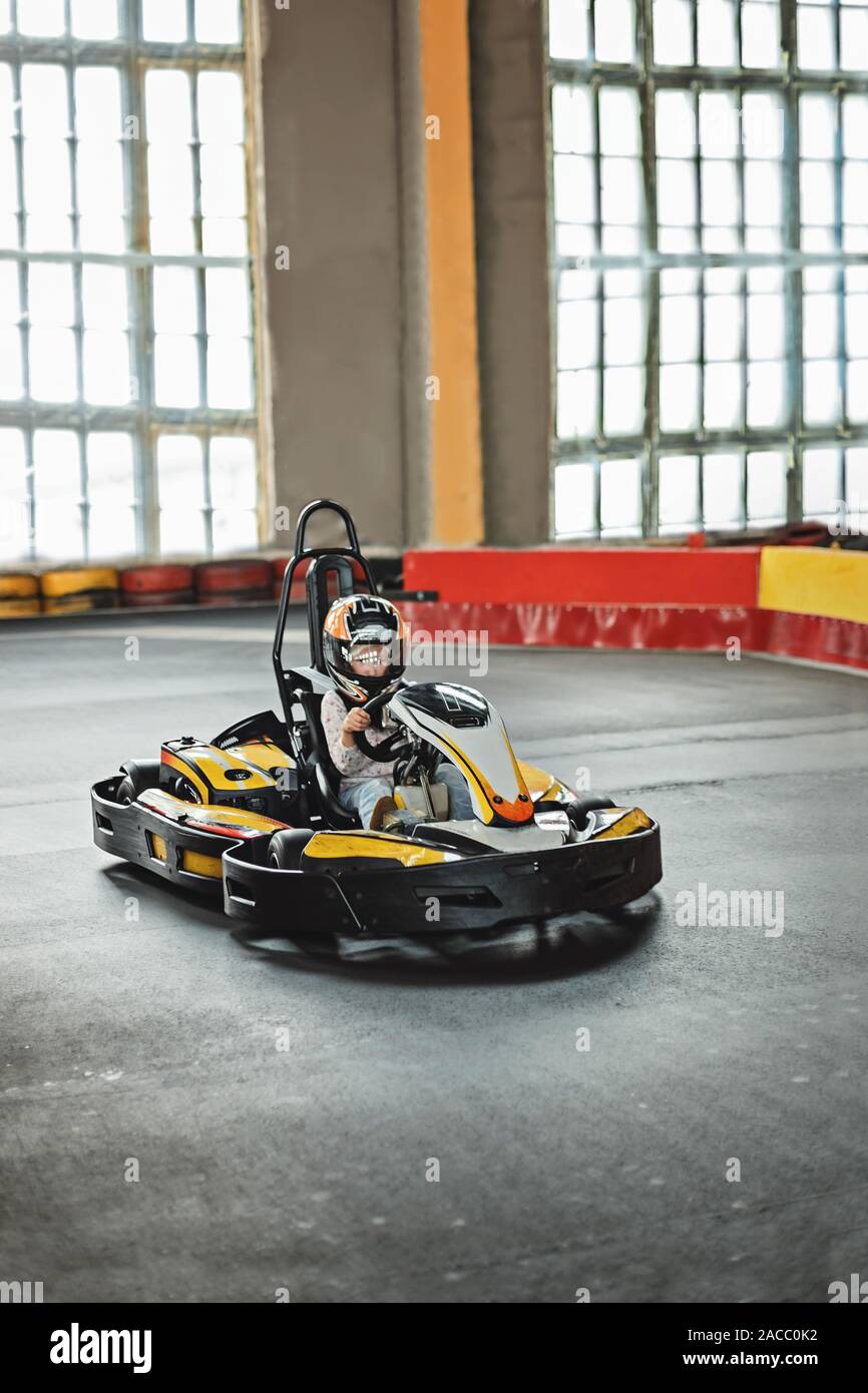 Children`s entertainment indoors. Girl driving go kart on the track. Active lifestyle. Stock Photo